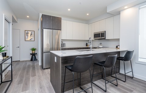 A kitchen with a white countertop and black chairs.