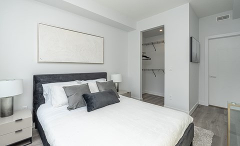 A bedroom with a large bed and a TV mounted on the wall.