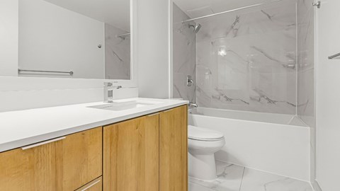 A white bathroom with a marble shower and a white toilet.