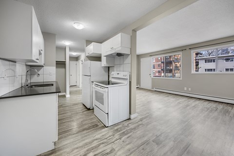 A modern kitchen with white appliances and wooden floors.
