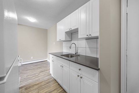 A kitchen with white cabinets and a black countertop.