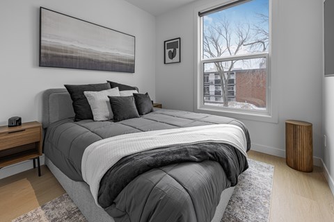 A bedroom with a large bed and a window showing a building outside.