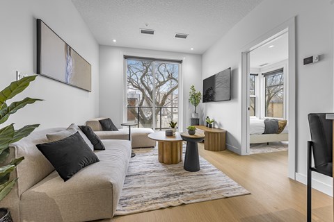 A living room with a beige couch and a large window.