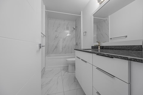 A white bathroom with a marble shower and toilet.
