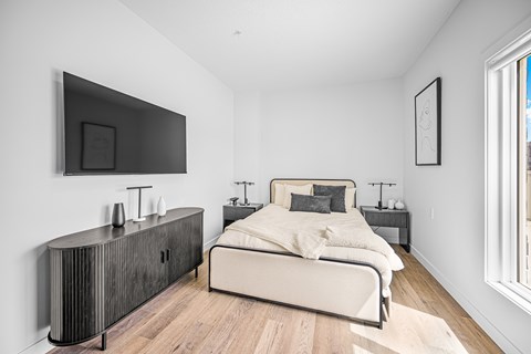 A modern bedroom with a large bed and a flat screen TV mounted on the wall.