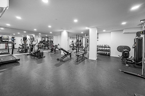 A black and white image of a gym with various exercise equipment.