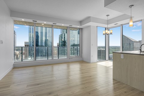 A spacious room with wooden floors and large windows overlooking a cityscape.
