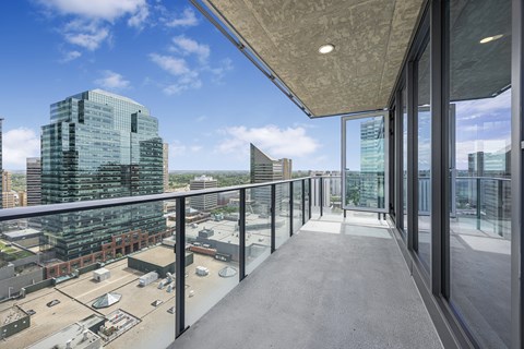 A long balcony with glass railings overlooks a cityscape.