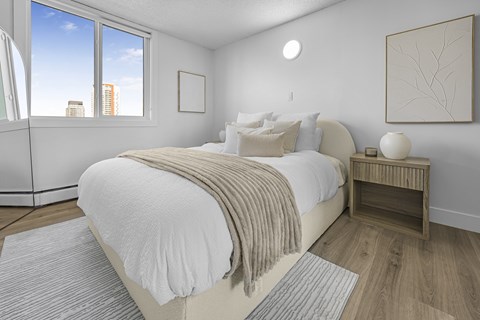 A bedroom with a large bed and a window overlooking the city.