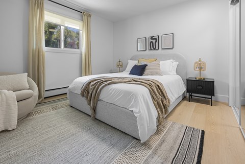 A bedroom with a large bed and a chair.