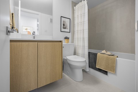 A white toilet sits in a bathroom next to a bathtub.