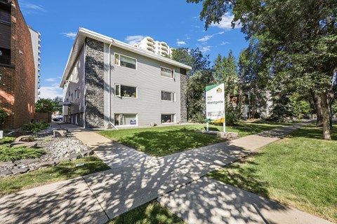 A sunny day at a residential area with apartment buildings and a sign that says "Welcome to Maple Grove".