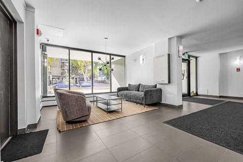 A spacious waiting room with a brown chair and grey couch.