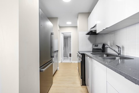 A modern kitchen with white cabinets and a black countertop.
