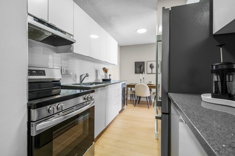 A modern kitchen with a black refrigerator and stove top oven.