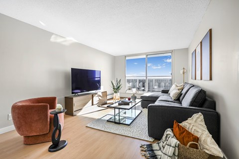 A living room with a grey couch, a red chair, a glass coffee table and a television.