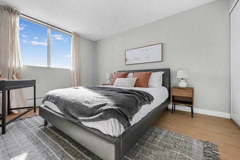 A bedroom with a large bed and a window overlooking the sky.