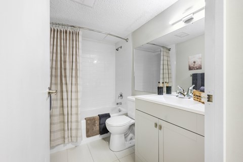 A white bathroom with a toilet, sink, and shower curtain.