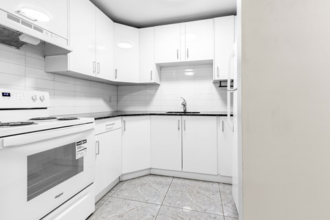 A white kitchen with a tile floor and white cabinets.
