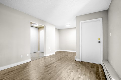 A room with a white door and a mirror on the wall.