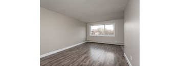 Empty room with wooden flooring and a window.