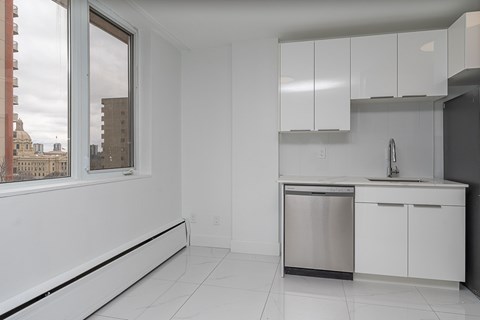 A kitchen with white cabinets and a window overlooking a cityscape.