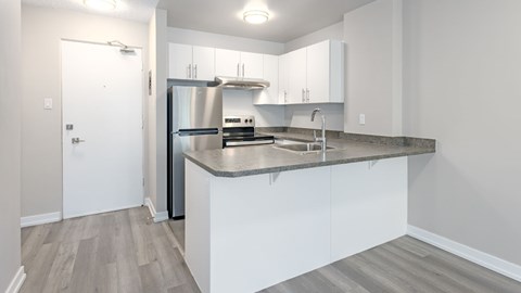 A modern kitchen with white cabinets and a stainless steel refrigerator.