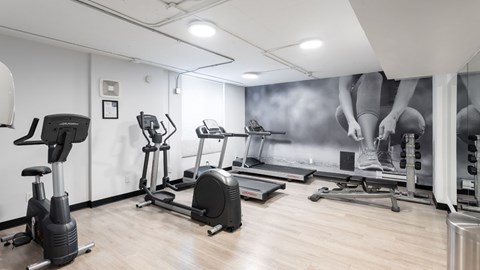 A gym with a variety of exercise equipment including treadmills, stationary bikes, and elliptical machines.