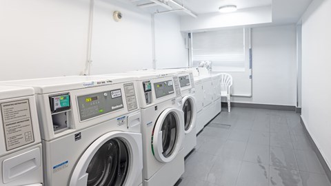 A row of industrial washing machines in a laundry room.