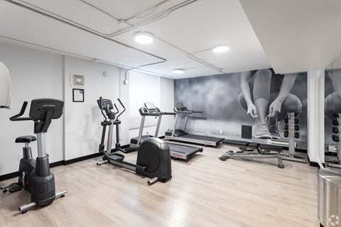 A gym with a variety of exercise equipment including treadmills, stationary bikes, and elliptical machines.