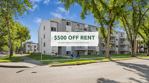 A modern apartment building with a $500 off rent sign in front.