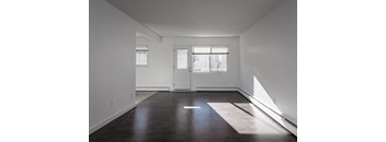 A room with a white door and a window with white blinds.
