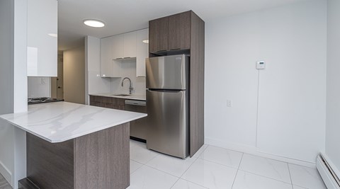 A modern kitchen with a stainless steel refrigerator and a white countertop.