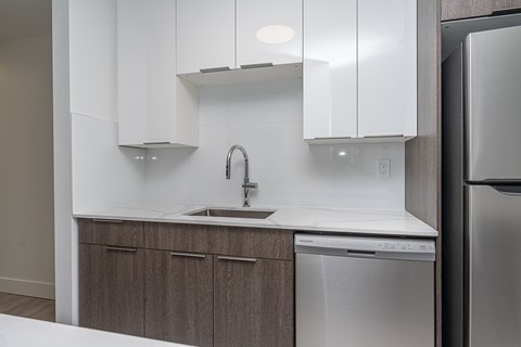 A modern kitchen with a stainless steel dishwasher and white cabinets.