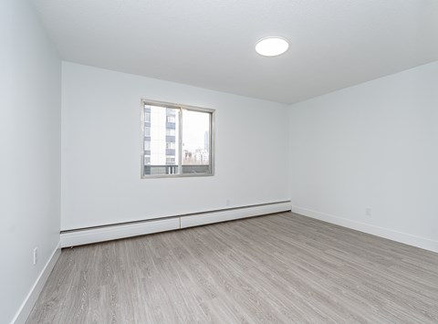 A room with a window and wooden flooring.