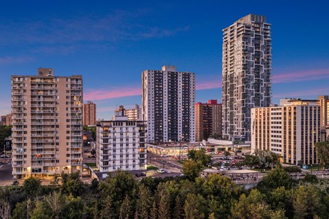 A cityscape with tall buildings and a parking lot in the foreground.