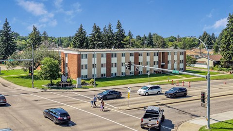 A street view of a road with cars and a building in the background.