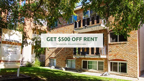 A sign offering $500 off rent is displayed in front of a brick building.