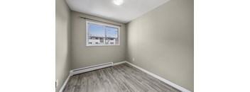 A room with a window showing a view of a building outside.