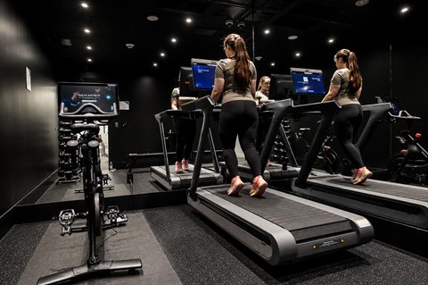 Three women are running on treadmills in a gym.