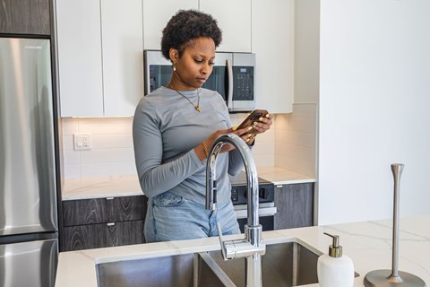 A woman is washing dishes in a modern kitchen.