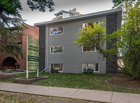 A sign for Leston Westgate Apartments is in front of a grey building.
