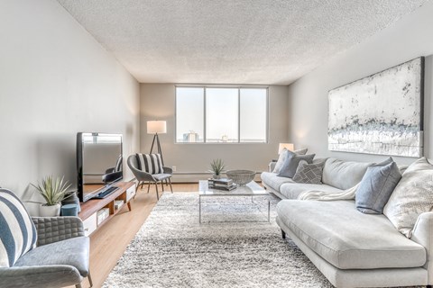 A living room with a grey couch, a striped chair, and a television.