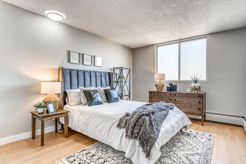 A bedroom with a bed, nightstand, and a window.