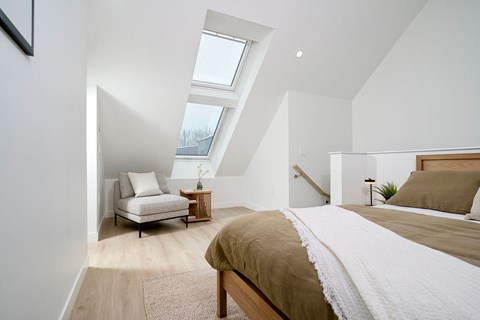 A bedroom with a bed, a chair, and a rug.