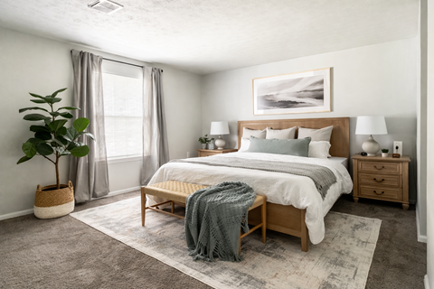 A bedroom with a large bed, a nightstand, and a plant.