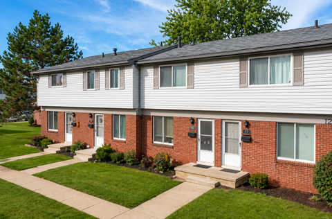 A row of houses with green lawns in front.