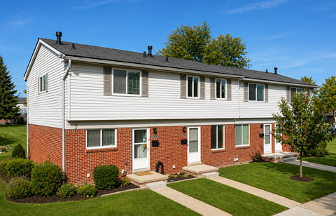 A two-story house with a red brick base and white siding.