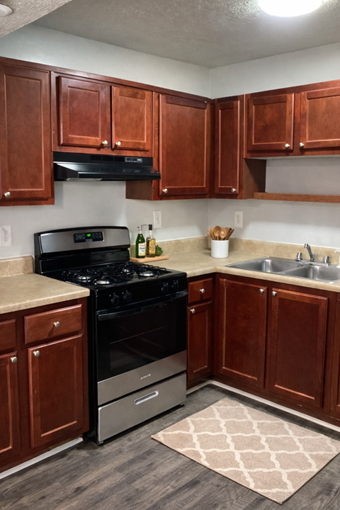 A kitchen with brown cabinets and a black stove top oven.