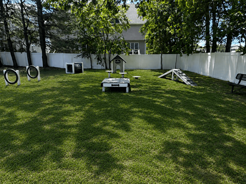 A backyard with a white fence and a dog house.